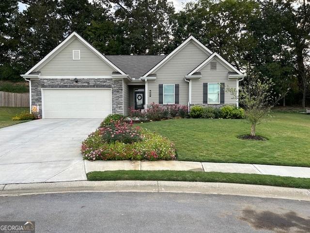 ranch-style house with a garage, a front yard, stone siding, and driveway