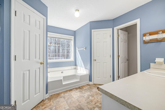 full bath with baseboards, a bath, a textured ceiling, vanity, and a closet