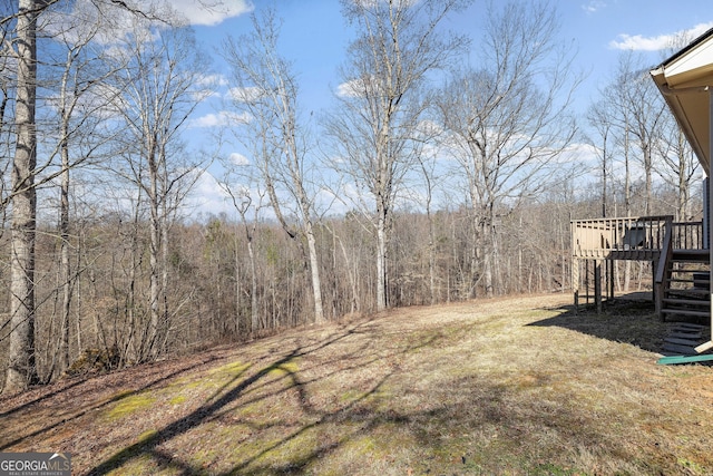 view of yard featuring stairway, a deck, and a wooded view