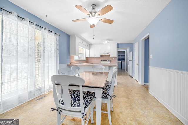 kitchen featuring white cabinets, stove, freestanding refrigerator, a peninsula, and under cabinet range hood