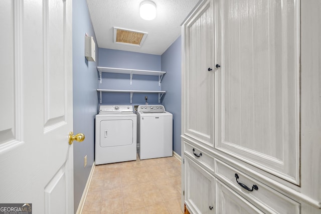 laundry area with a textured ceiling, light tile patterned floors, baseboards, independent washer and dryer, and cabinet space