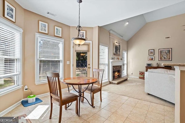 dining area with lofted ceiling, visible vents, a fireplace, and light tile patterned floors