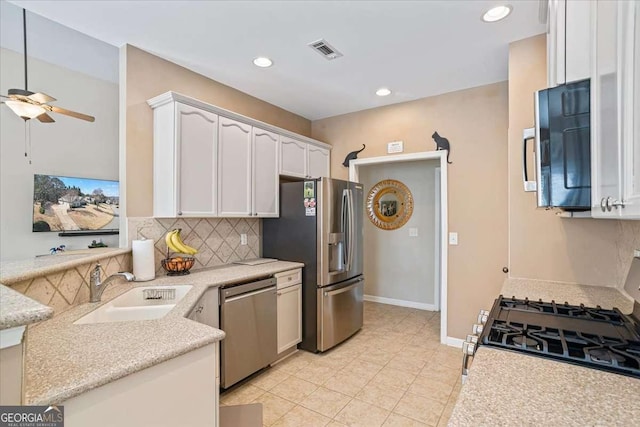 kitchen featuring stainless steel appliances, a sink, visible vents, white cabinets, and backsplash