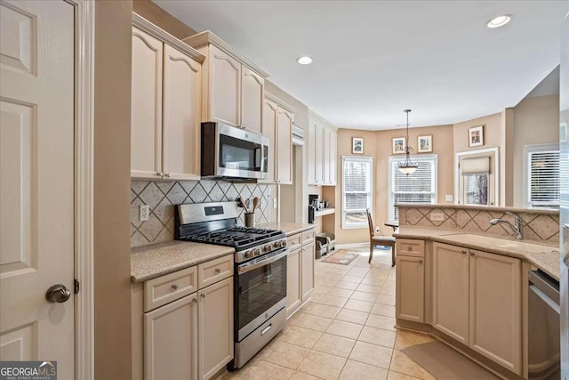 kitchen with hanging light fixtures, decorative backsplash, appliances with stainless steel finishes, light tile patterned flooring, and a sink