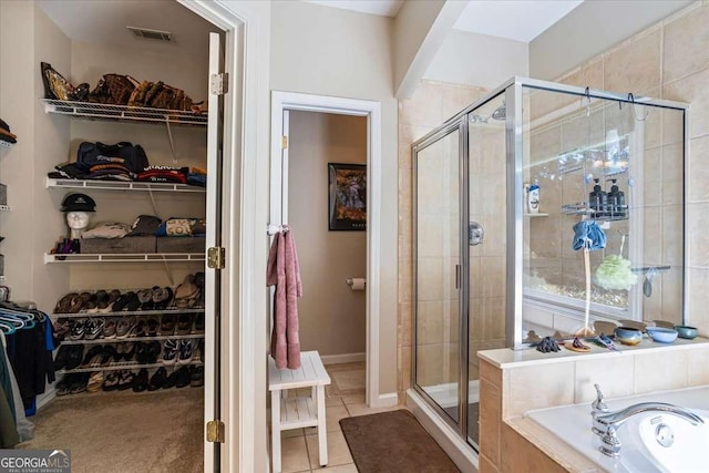 full bath with a stall shower, tile patterned flooring, and a walk in closet