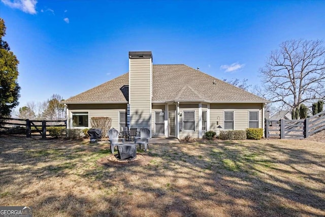 rear view of house featuring a fenced backyard, a chimney, a shingled roof, and a lawn