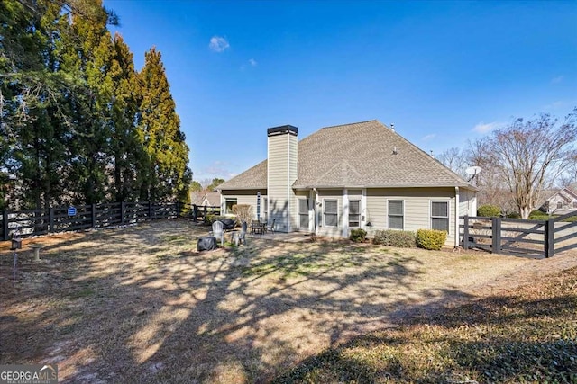 rear view of house featuring a chimney and a fenced backyard