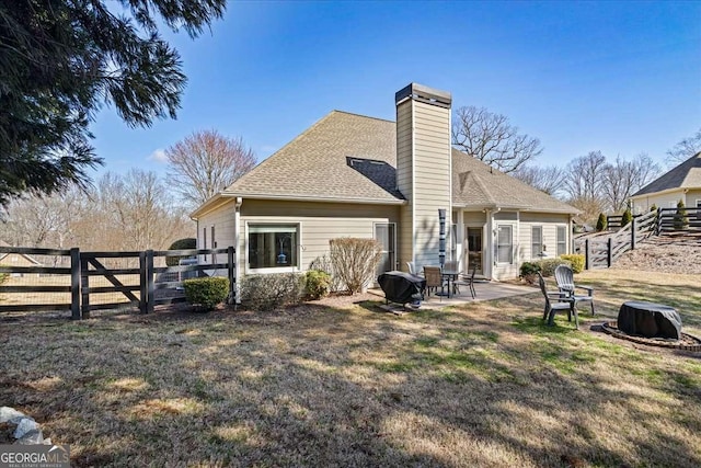 back of house with roof with shingles, a chimney, a patio area, and a fenced backyard