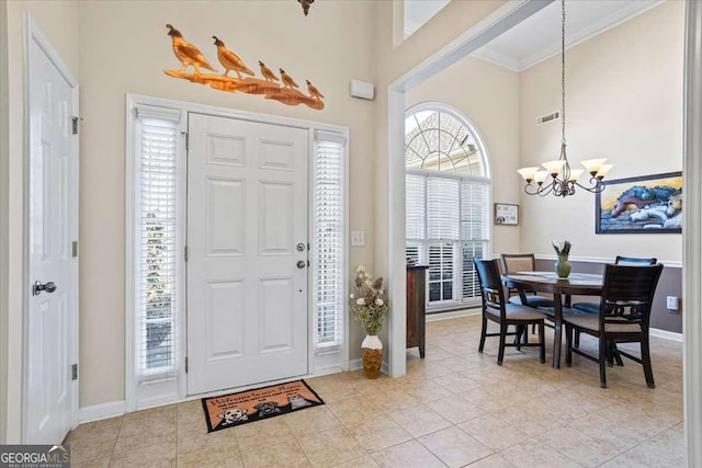 entrance foyer with a towering ceiling, an inviting chandelier, light tile patterned floors, and visible vents