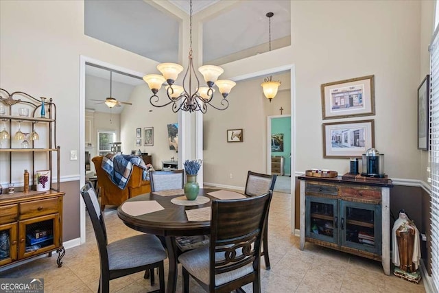 dining area with light tile patterned floors, ceiling fan with notable chandelier, a towering ceiling, and baseboards