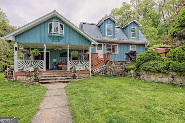 view of front facade with a porch, a front yard, and metal roof