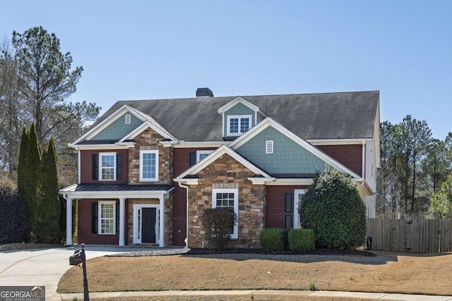 view of front facade featuring stone siding, a chimney, fence, and brick siding