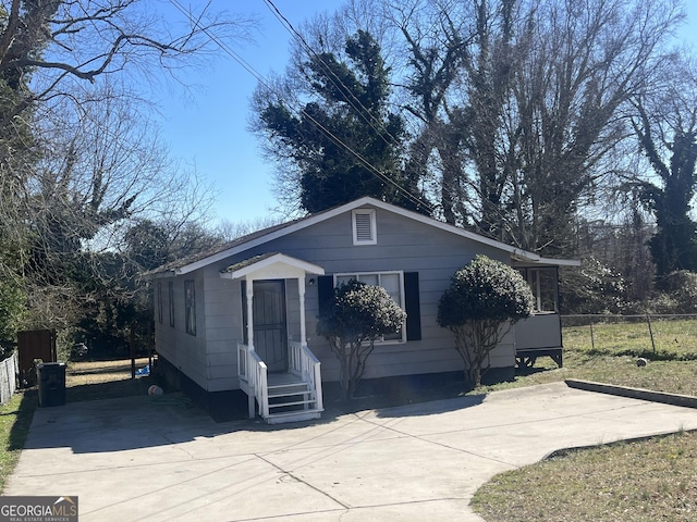 bungalow-style home featuring concrete driveway and fence