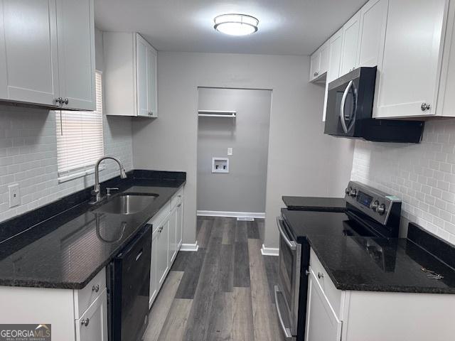 kitchen featuring dark wood-type flooring, a sink, baseboards, white cabinets, and appliances with stainless steel finishes