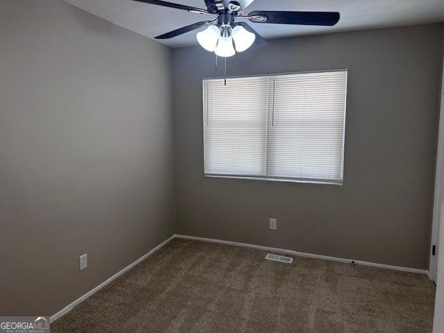 empty room featuring ceiling fan, dark colored carpet, visible vents, and baseboards