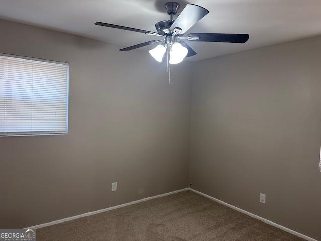 carpeted empty room featuring a ceiling fan and baseboards