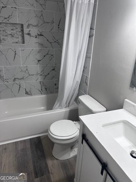 bathroom featuring toilet, vanity, wood finished floors, and shower / bath combo with shower curtain