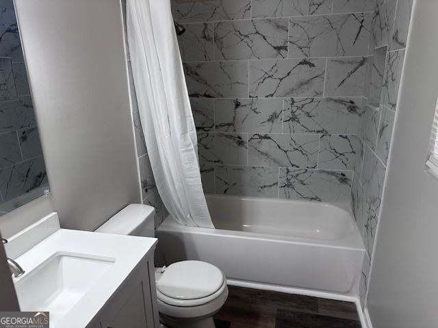 full bath featuring vanity, wood finished floors, toilet, and shower / tub combo with curtain