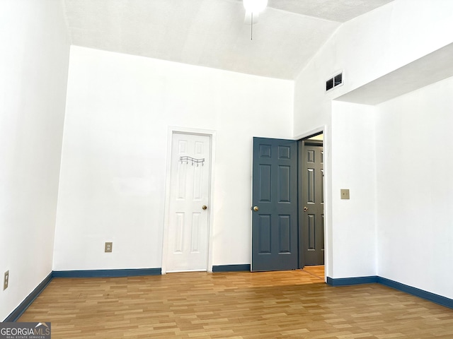 spare room featuring high vaulted ceiling, light wood-type flooring, and baseboards