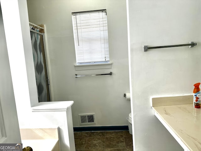 bathroom featuring a shower, baseboards, visible vents, and toilet