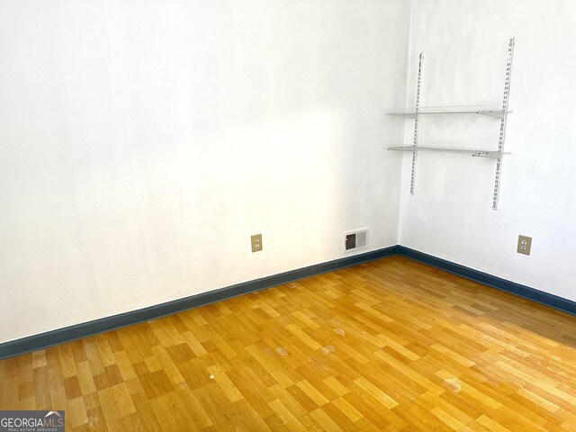 spare room with wood finished floors, visible vents, and baseboards