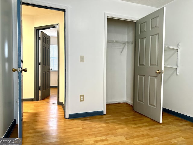 unfurnished bedroom featuring light wood-style floors, a closet, and baseboards