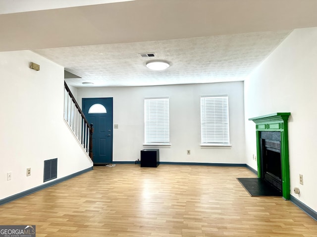 entrance foyer with light wood finished floors, stairs, visible vents, and a textured ceiling