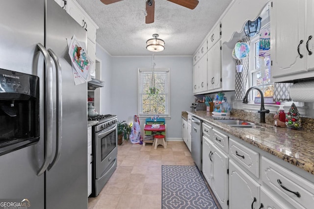 kitchen featuring ceiling fan, dark stone countertops, stainless steel appliances, white cabinetry, and a sink