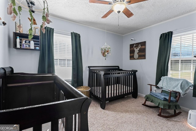 bedroom featuring ceiling fan, carpet, a textured ceiling, crown molding, and a nursery area