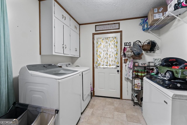 washroom featuring ornamental molding, cabinet space, washer and clothes dryer, and a textured ceiling