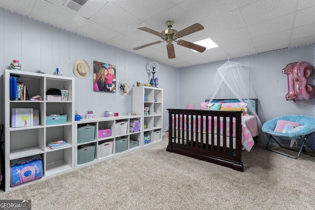 carpeted bedroom featuring a drop ceiling, visible vents, and a ceiling fan