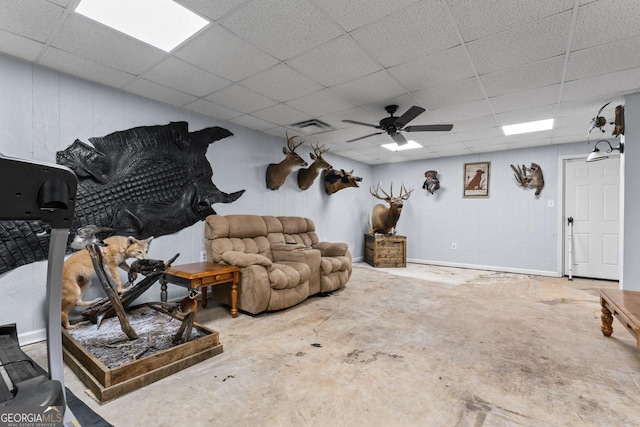 living room featuring concrete floors, a drop ceiling, visible vents, and a ceiling fan