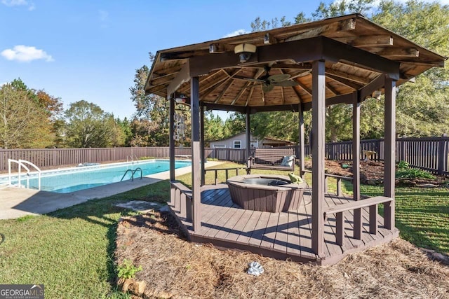 view of swimming pool featuring ceiling fan, a gazebo, a fenced backyard, and a hot tub