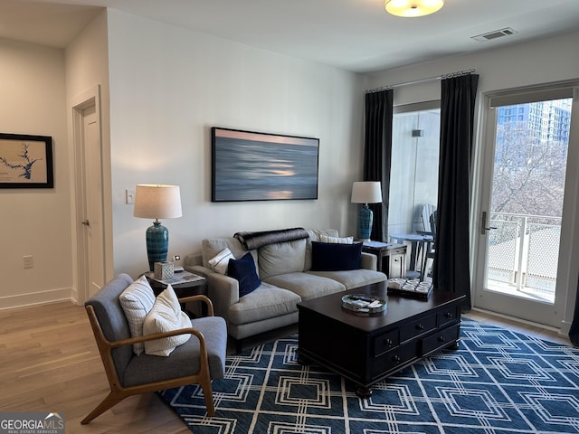 living room featuring baseboards, dark wood finished floors, visible vents, and a healthy amount of sunlight