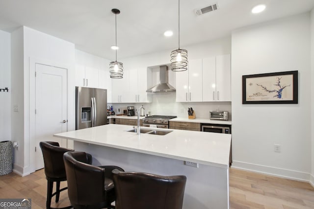 775 Juniper St NE Unit 613, Atlanta, GA 30308 - kitchen with wall chimney range hood, stainless steel appliances, light wood-style flooring, a kitchen bar, and recessed lighting