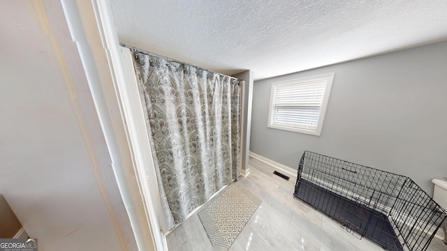 bathroom featuring baseboards, a textured ceiling, visible vents, and wood finished floors