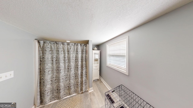 bathroom with a textured ceiling, wood finished floors, and baseboards