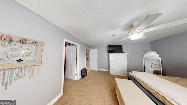 bedroom featuring light carpet, ceiling fan, a textured ceiling, and baseboards