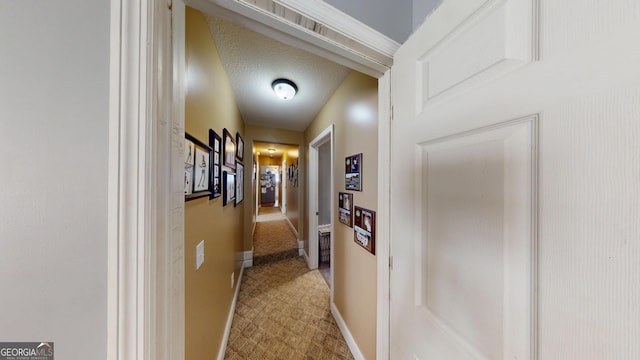 corridor with a textured ceiling and baseboards