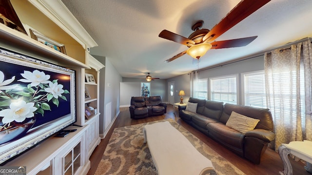 living room featuring ceiling fan, dark wood-style flooring, a textured ceiling, and baseboards