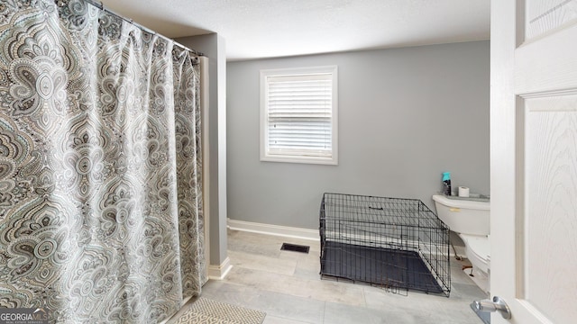 bathroom with toilet, visible vents, and baseboards