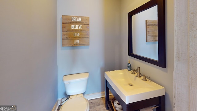 bathroom featuring toilet, baseboards, and a sink