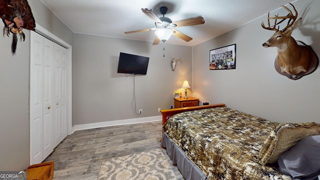 bedroom with light wood-style floors, a closet, ceiling fan, and baseboards