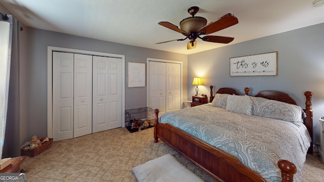 bedroom with ceiling fan, light colored carpet, and multiple closets