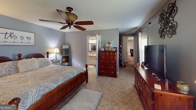 bedroom with a ceiling fan, light colored carpet, and connected bathroom