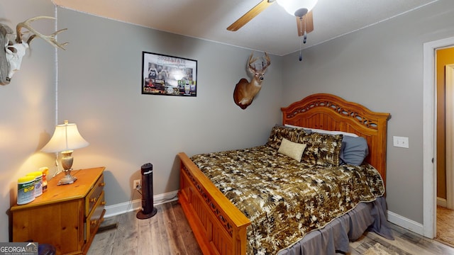 bedroom with a ceiling fan, baseboards, and wood finished floors