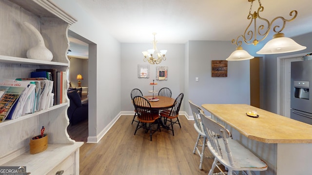 dining area featuring baseboards, an inviting chandelier, and light wood-style floors