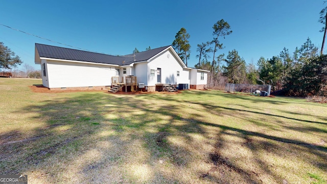 back of property with metal roof, crawl space, a lawn, and central air condition unit