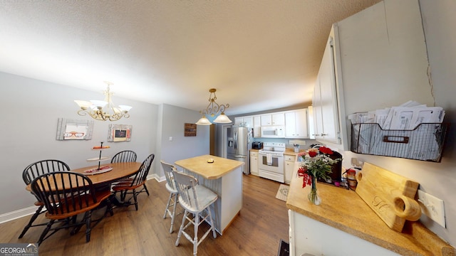 kitchen featuring white cabinets, white appliances, light countertops, and decorative light fixtures