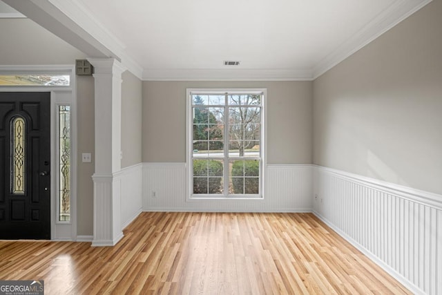 entrance foyer with visible vents, wainscoting, ornamental molding, wood finished floors, and ornate columns